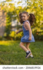 Baby Toddler Running On Green Lawn Near The House.