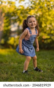 Baby Toddler Running On Green Lawn Near The House.