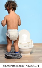 Baby Toddler Sitting Near The Potty And Playing With Toilet Paper. Cute Kid Potty Training For Pee And Poo