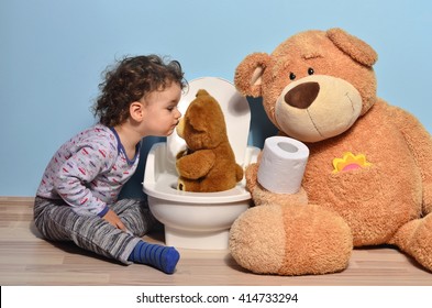 Baby toddler sitting on the floor near a potty and kissing a teddy bear. Cute kid potty training for pee and poo helped by teddy bear who gives him toilet paper