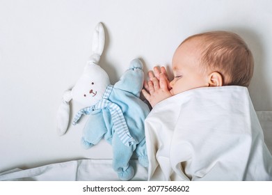 Baby With Toy In Hands Sleeps On Bed. Infant Development Concept, Toddler Restful Sleep, Teething, Colic.