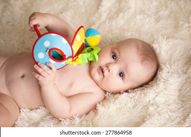 Baby With Toy Lying On A Blanket