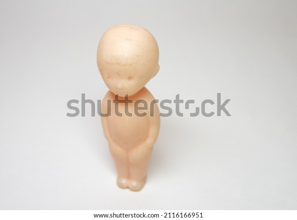 baby toy plastic figure. little boy, standing\
straight. Doll with no moving parts. Head with bangs on forehead.\
selective focus