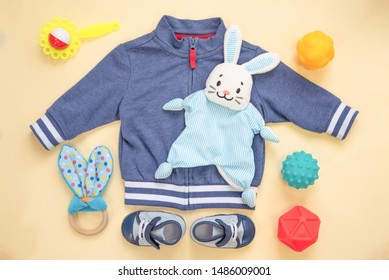 Baby Toys, Boots And Clothes On A Orange Flay Lay Background.