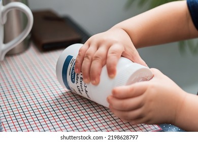 Baby Trying To Reach And Open A Child Proof Medical Container; Bottle With Vitamins