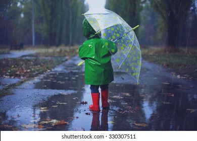 Bebê andando no parque chuvoso de outono