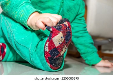 Baby In Warm Clothes Trying To Remove Sock Full Of Cat Hair Or Fur