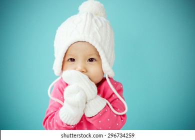 Baby with white poodle hat and knitted mittens on the blue background in winter season, Baby healthy and winter concept - Powered by Shutterstock