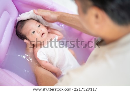 A baby whose head is washed in a bath