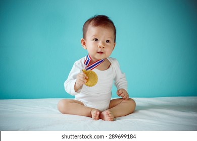 The Baby Winner Holding A Golden Medal And Sitting On A Bed In The Blue Room, Baby Healthy And Preschool Concept