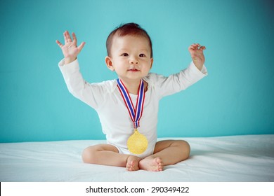 The Baby Winner Holding A Golden Medal And Sitting On A Bed In The Blue Room, Baby Healthy And Preschool Concept