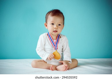 The Baby Winner Holding A Golden Medal And Sitting On A Bed In The Blue Room, Baby Healthy And Preschool Concept