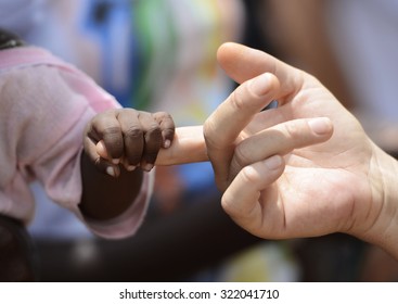 Baby and woman hold hands in Bamako, Mali. A beautiful shot with lots of possible background symbols. No to Racism!