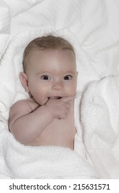 baby wrapped in white towel after bath, looking at camera