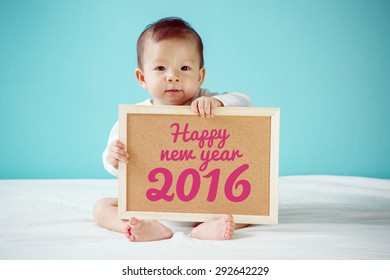 Baby writing "Happy New Year 2016" on the board, new family concept.