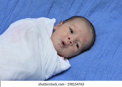 Baby Yawning During Sleep In White Swaddle