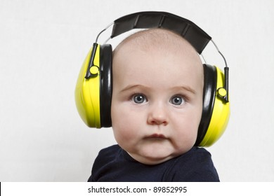 Baby mit gelbem Ohrschutz in lauter Umgebung. neutraler grauer Hintergrund