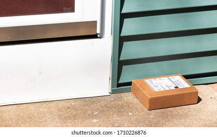 Babylon, New York, USA - 1 April 2020: A Small Cardboard Package Is Deleverd And Left Out In View On Resedental Front Stoop.