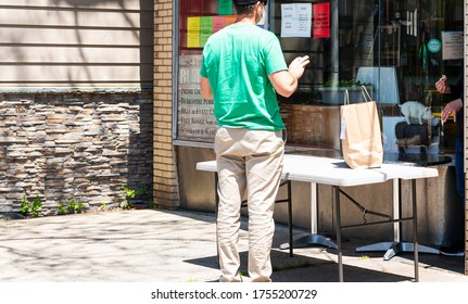 Babylon, New York, USA - 13 May 2020: Man Picking Up His Food Curbside During The Coronavirus COVID-19 Pandemic.