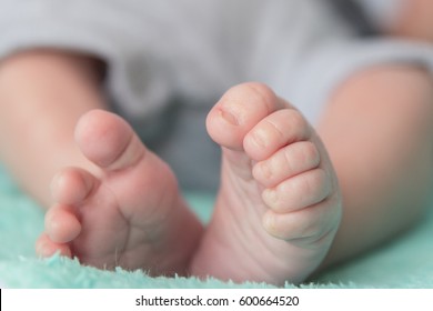 Baby's Feet And Curled Toes Closeup On Turquoise Blanket Sleeping