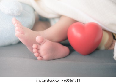 baby's feet with a red heart - Shutterstock ID 606864713