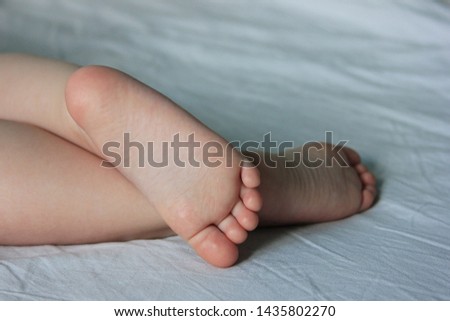The baby`s feet. The toddler is sleeping on the bed. Closeup the cute foot