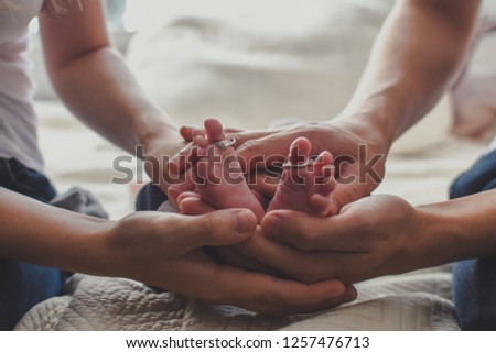 Baby's feet with wedding rings of parents on toes of fingers. All together