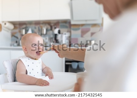 baby's first feeding, mom feeds a surprised baby with a spoon. High quality photo