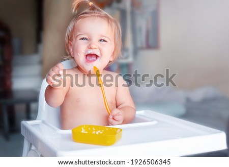 Similar – Image, Stock Photo Cute baby eating first solid food, infant sitting in high chair. Child tasting vegetables at the table, discovering new food. Cozy kitchen interior. Healthy food concept.