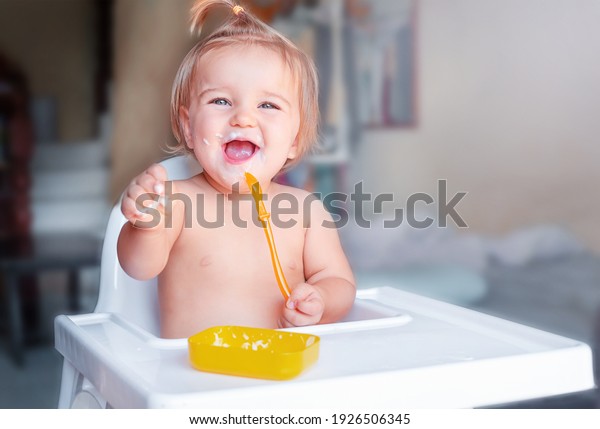 Baby\'s\
first meal. The child eats on his own with a\
spoon
