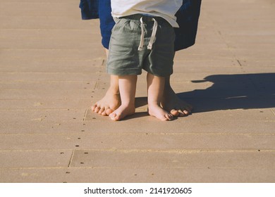 Baby's First Steps. Mother And Small Child Walking Barefoot On Beach Sand Near By Ocean. Happy Young Family In Nature. Mother And Baby Playing Outdoors On Sea Beach. Close-up Human Feet.