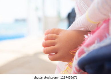 A baby's small leg of a sleeping child and looks out of the stroller against the backdrop of a summer sunny blurred landscape. A small, plump leg of a child sleeping near the sea.