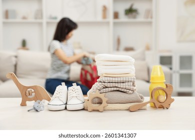 Baby's stuff on white table and mother packing bag, selective focus