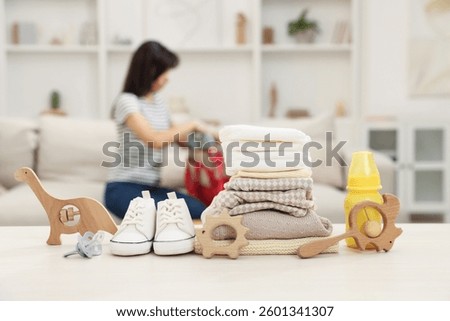 Baby's stuff on white table and mother packing bag, selective focus