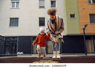 A babysitter teaching a child how to play hopscotch at the playground. - Powered by Shutterstock