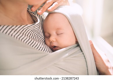 Babywearing. Mother and baby on nature outdoors. Baby in wrap carrier. Woman carrying little child in baby sling in green mint color. Concept of green parenting, natural motherhood, postpartum period.
