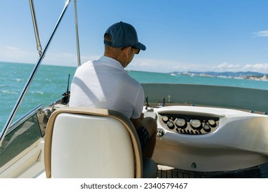Bach view of middle-aged man driving luxury motor yacht. Captain at the helm of motor boat. Image with selective focus