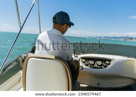 Bach view of middle-aged man driving luxury motor yacht. Captain at the helm of motor boat. Image with selective focus