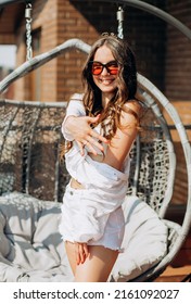 Bachelorette Party. Happy Future Bride In A White Shirt And Shorts Poses On The Roof Of The House Overlooking The City.