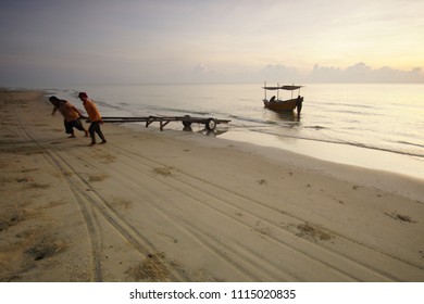 BACHOK, MALAYSIA 15JUN 2018: A Group Of Fishermen Help Each Other To Push Their Boat Into The Water. The Are Doing This Every Morning To Reduce Heavy Workload.