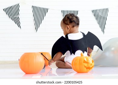 Back Of Adorable African Baby Kid Dressing Up In Vampire Fancy Halloween Costume With Black Bat Wings, Cheerful Little Cute Child Go To Party, Playing Trick Or Treat, Happy Halloween Celebration.