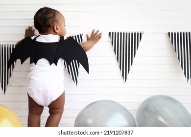 Back Of Adorable Baby Kid Dressing Up In Vampire Fancy Halloween Costume With Black Bat Wings, Cheerful Little Cute Child Go To Party, Playing Trick Or Treat, Happy Halloween Celebration.