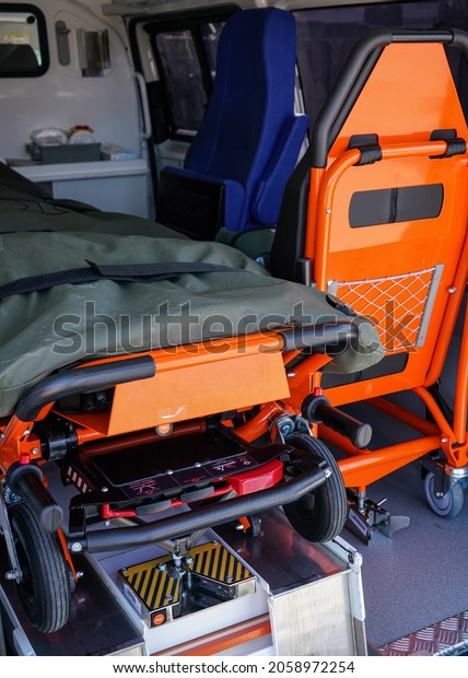 Back of ambulance vehicle, bright orange\
carrying stretcher and patient chair\
visible