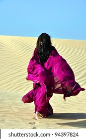 Back of arabic brunette woman walking away in desert