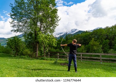 Back of archery athlete aiming at a target. Young archer training with the bow. Archery hunter practicing with Italian Alps in the background  - Powered by Shutterstock