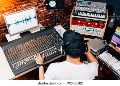 back of asian male music producer, sound engineer, composer, dj working in studio. recording, broadcasting, audio video editing concept - Powered by Shutterstock