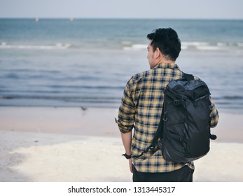 Back Of Asian Man With Backpack Standing And Looking At The Beach.