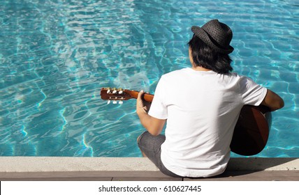 Back Of Asian Man Play Guitar On Pool Water In Summer