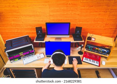 Back Of Asian Music Producer Working In Home Studio. Music Production Concept