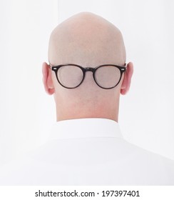 back of a bald-headed man in a white shirt with glasses on
